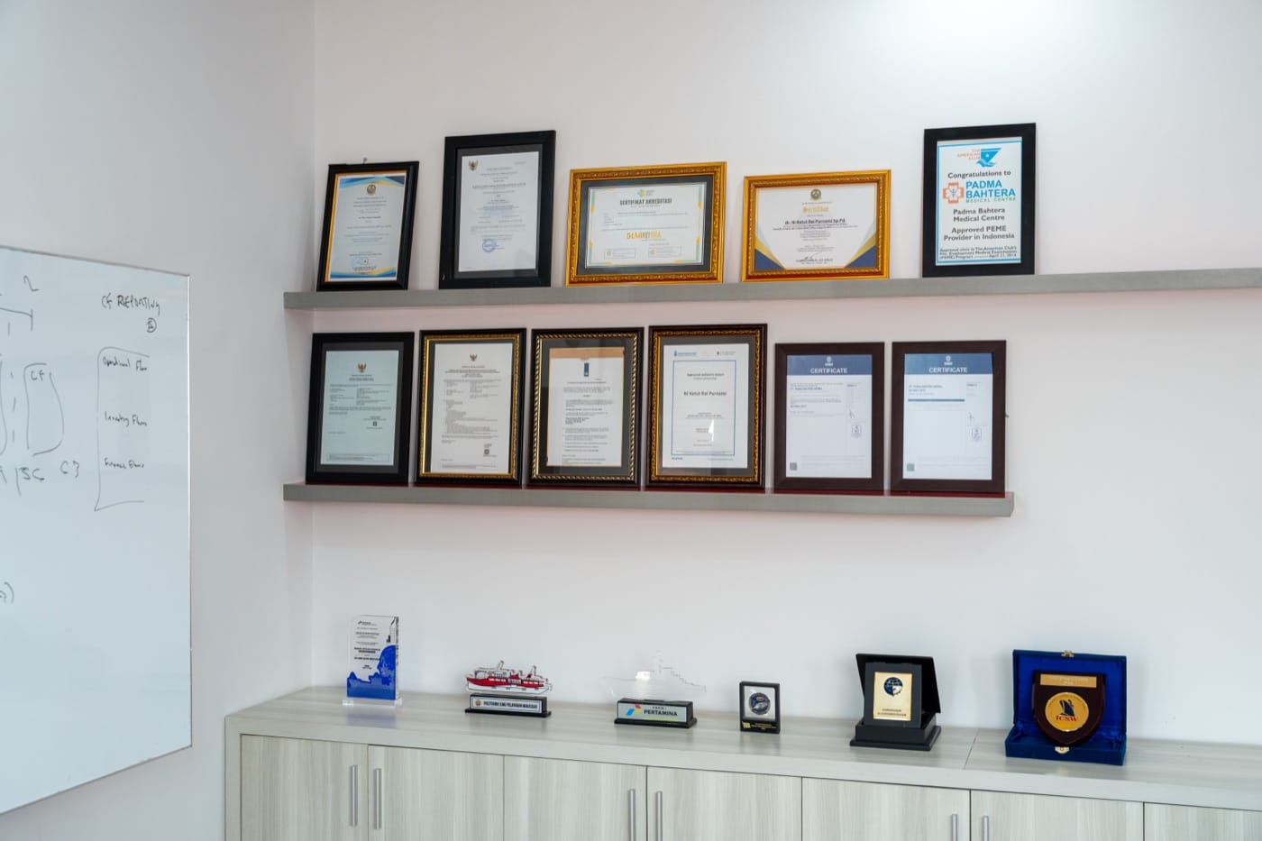 A wall of framed licenses and certifications at the medical center reception.